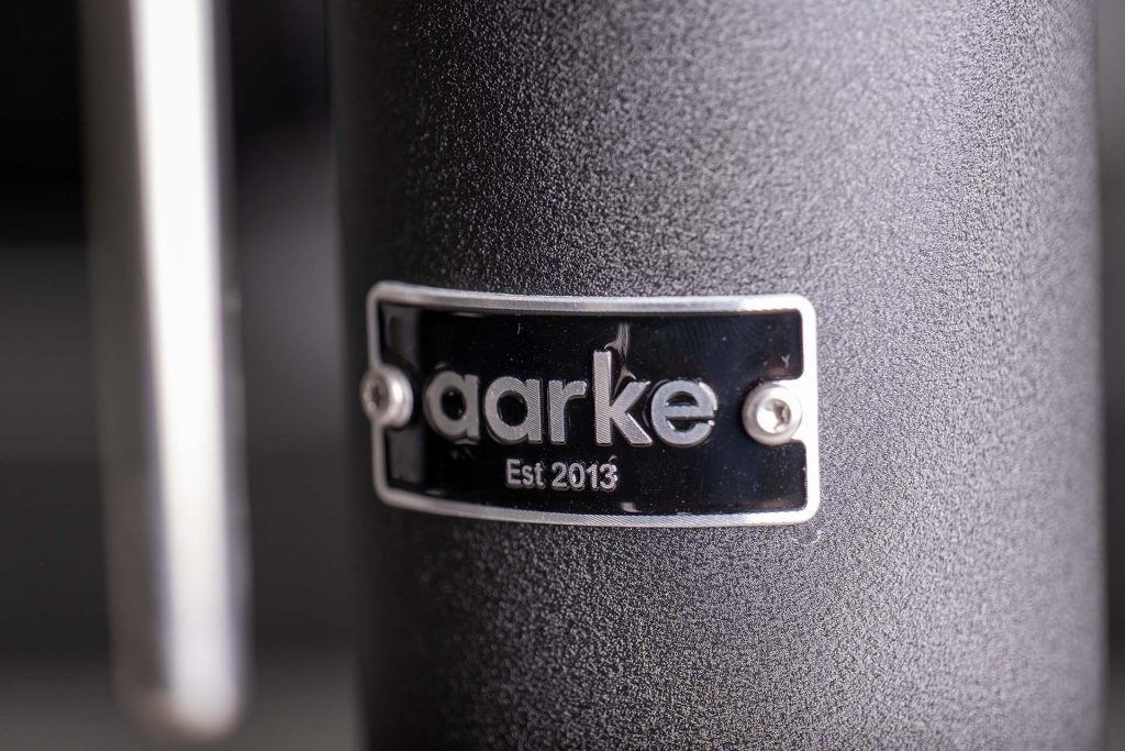 Close-up of the Aarke brand logo on a matte black soda maker, showcasing the brand's establishment year, 2013. The focus on the metallic label emphasizes the high-quality craftsmanship and attention to detail in the product's design. This image highlights the premium build and modern aesthetic, making it a centerpiece in any kitchen setting.