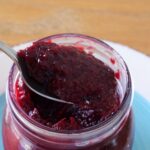 Spoonful of homemade Powidl plum butter held over an open jar