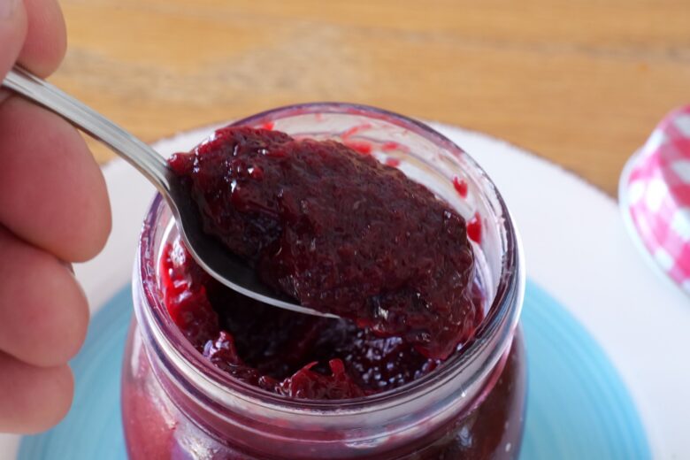 Spoonful of homemade Powidl plum butter held over an open jar